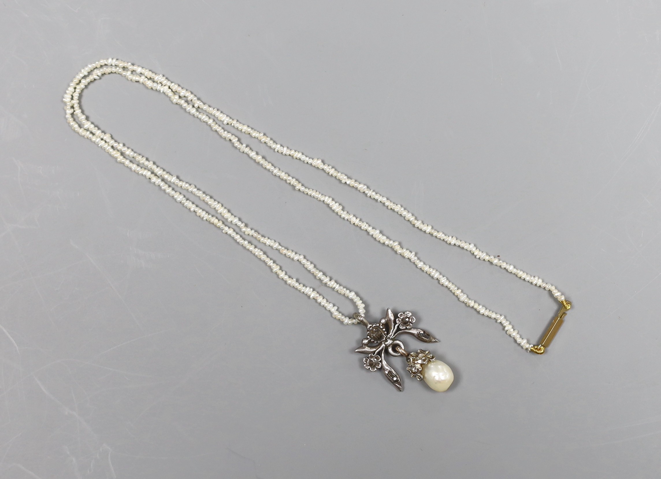 An Indian rose diamond and baroque pearl white metal mounted drop pendant, on a seed pearl necklace